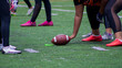 © Milagros Riquelme/Wirestock Creators - Closeup shot of an American football ball between players hands during a match on a green field