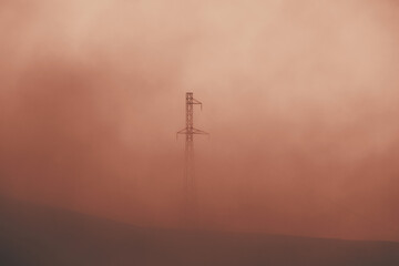 electric power transmission lines in smoke. high voltage post. industrial landscape. electricity pyl