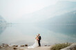 Couple romantically posing at elopement in foggy misty mountain lake