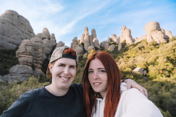 two young men and hikers, taking a selfie from the top of the mountain with their smartphone. Monserrat Spain