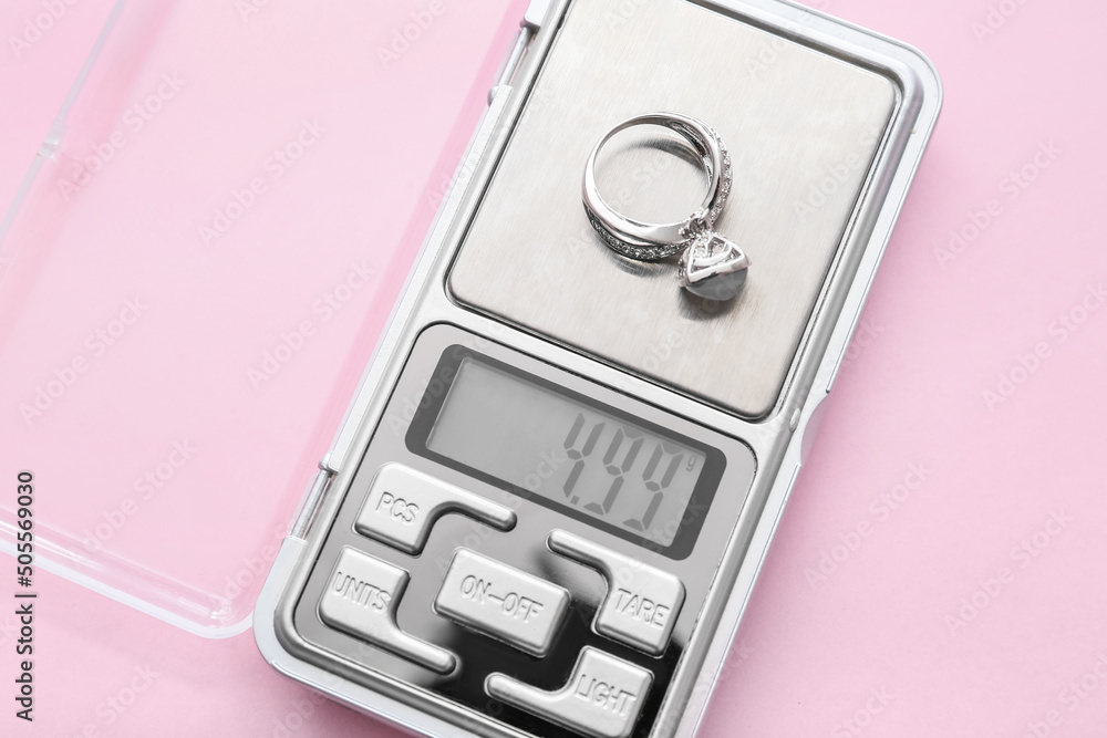 Jewelry scales with ring on pink background