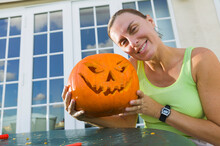 A Woman Holding A Halloween Carved Pumkin Face