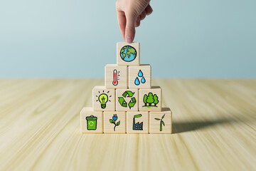 Poster - Wooden cubes with pictures of Earth, ecology, rain, temperature, forests, plants. A hand places a cube with Earth. Concept of caring for the environment, ecology, caring for the planet earth.