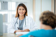 © chokniti - Portrait of smiling young female doctor writing prescription and tests for senior patient sitting on wheelchair in cabin with physician in hospital