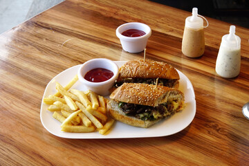 Canvas Print - Cheeseburger with french fries and a sauce in a white plate on a wooden table