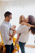 © EGHStock - Family of four with newborn baby holding by dad. mom kissing older sister
