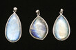 © Ho Man Wai/Wirestock Creators - Pendants made of rainbow moonstone behind a black surface