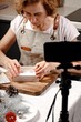 Woman making handmade chocolates and creates content for social media. Live broadcasts from the camera of a mobile smartphone of a master class on making sweets, chocolate truffles. Vertical shot