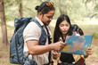 Man and woman Asian backpacker trekking planning and looking at map in the forest, Teamwork outdoor activity. Trekking. Camping and wild life concept.