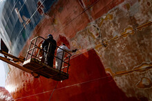 Workers Working In A Shipyard And Painting In Naval Industry