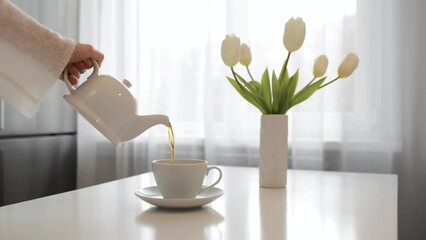 Wall Mural - A woman's hand pours tea from a teapot