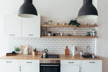 Modern new light interior of kitchen with white furniture and dining table.