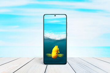 Goldfish in a mobile phone as an aquarium concept. Creative composition with sea and fish in mobile phone