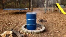 Blue Painted Metal Barrel Being Heated On Fire Pit To Remove All Paint