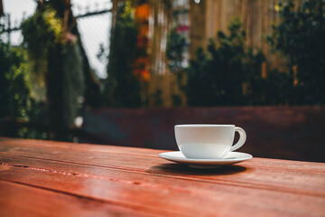 cup of coffee on wooden table in morning sun