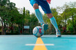 Image of a man starting a dribble with the ball on the yellow line. Close-up image of a young boy with white socks and a sweatshirt dodging his rival on a blue soccer field with the goal in the back.