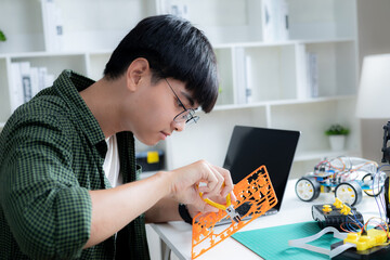 Asian teenager doing robot arm project in house,