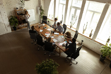 Wall Mural - Aerial view of young people, co-workers during work process, meeting at office, indoors. Work, finance, tech and business concept.