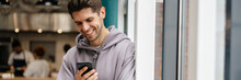 Happy Young Brunette Man Holding Mobile Phone