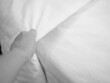 Closeup of white bed sheet or duvet surface with blurry women 's hand for room cleaning, preparing in hotel or home