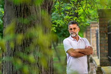 Poster - Portrait of Senior man Caucasian smiling and looking at camera, outside in park. Portrait of young attractive men in outdoor environment with confident and inspiring attitude.