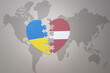 puzzle heart with the national flag of ukraine and latvia on a world map background. Concept.