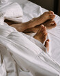 Female and male feet under blanket in bed