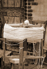 Antique Wooden Spinning Wheel With A Skein Of Wool Below And A Ball Of Yarn Above With Sepia Effect