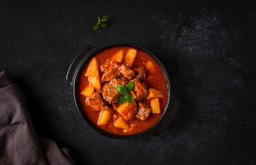 Wall Mural - Stew with potatoes, in tomato sauce, with spices and herbs, close-up, no people, on a black background