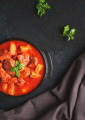 Wall Mural - Stew with potatoes, in tomato sauce, with spices and herbs, close-up, no people, on a black background