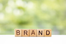 Brand - Word Is Written On Wooden Cubes On A Green Summer Background. Close-up Of Wooden Elements.