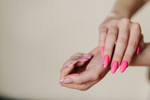 Photo Of Female Hands On An Empty Wall With Pink Manicure. One Hand Above The Other Below. Hands In The Air.