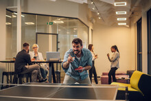 Young People Playing Table Tennis In The Office At Work