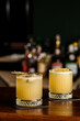 Warm colored cocktails. Mezcal cocktail and Alcoholic Scotch Whiskey Penicillin Drink Cocktail. Cocktail glass on bar counter