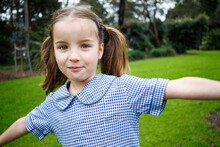 Close Up Shot Of A School Girl In Uniform Playing Outside With Her Arms Out