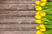 A Stack Of Yellow Tulips On A Wooden Desk. A Ready Place For Your Invitation Text.