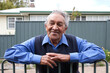 © Austockphoto - Elderly indigenous man smiling for camera while leaning on fence