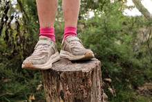 Person Wearing Dirty Old Sneakers Shoes On A Stump