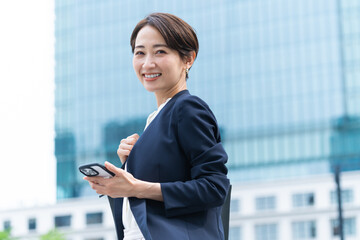 Wall Mural - 携帯を持ちカメラ目線の見つめるきれいな日本人女性・ビルバック