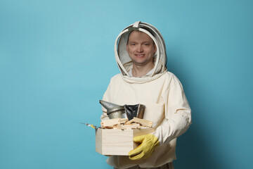 Wall Mural - Beekeeper in uniform with tools on light blue background