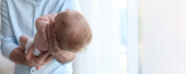 Sticker - Father holding his newborn baby at home, closeup view with space for text. Banner design