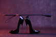 Black shiny high heel shoes and a whip on a dark background
