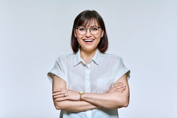 Wall Mural - Portrait of positive confident middle aged woman looking at camera, on light background