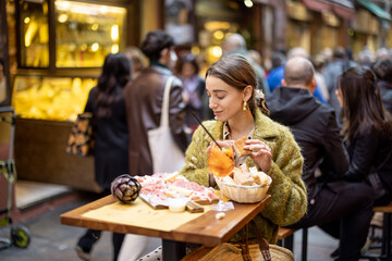 Wall Mural - Woman eating italian meat appetizer, various sliced meat and cheese with bread and Aperol Spritz at bar or restaurant outdoors. Concept of Italian lifestyle and gastronomy