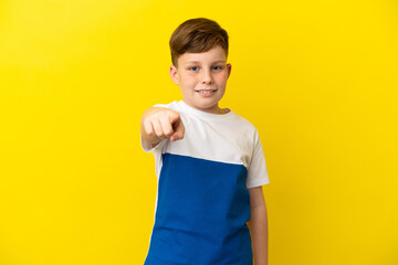 Wall Mural - Little redhead boy isolated on yellow background surprised and pointing front