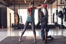 African American Young Male Coach Giving Boxing Training To Caucasian Young Woman In Health Club