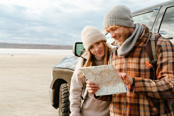 Wall Mural - White couple smiling and examining map together during car trip