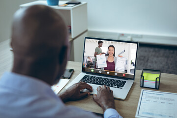 Wall Mural - Smiling asian businesswoman showing graphs and reports to african american male colleague on laptop