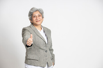 Wall Mural - Portrait of a confident mature senior indian business woman in a suit do thumbs up isolated on white background. successful gray-haired 60s asian lady executive manager standing, copy space.