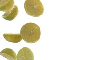 Close-up Of The Halves Of Fresh Limes Falling Down On The White Background